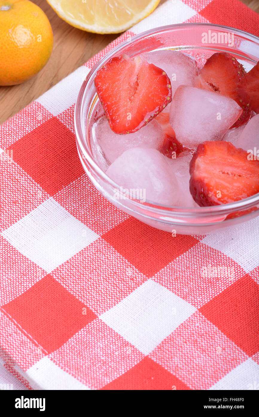 Une tranche de fraise rouge sur plaque de verre avec citron et mandarin dans l'arrière-plan thème de partie Banque D'Images