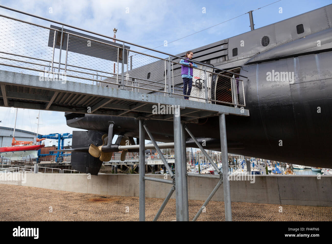 Une jeune fille se tient sur la passerelle métallique qui permet aux visiteurs de quitter le sous-marin de la DEUXIÈME GUERRE MONDIALE, L'Alliance HMS Gosport. Banque D'Images