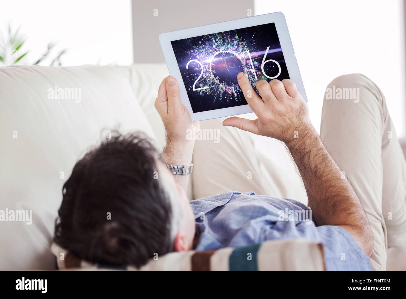 Image composite de l'homme portant sur canapé à l'aide d'un tablet pc Banque D'Images