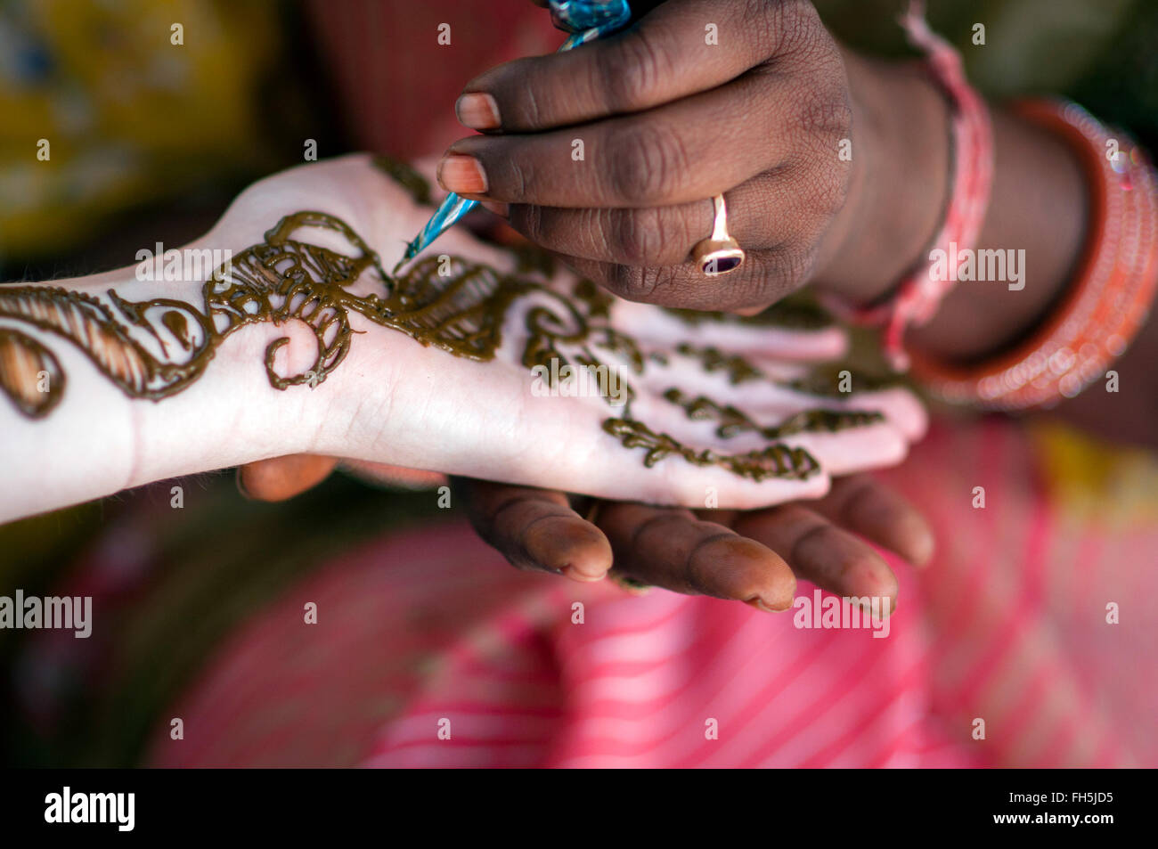 Mains d'une femme indienne d'appliquer la pâte de henné main tendue de la femme avec la peau blanche pâle Banque D'Images