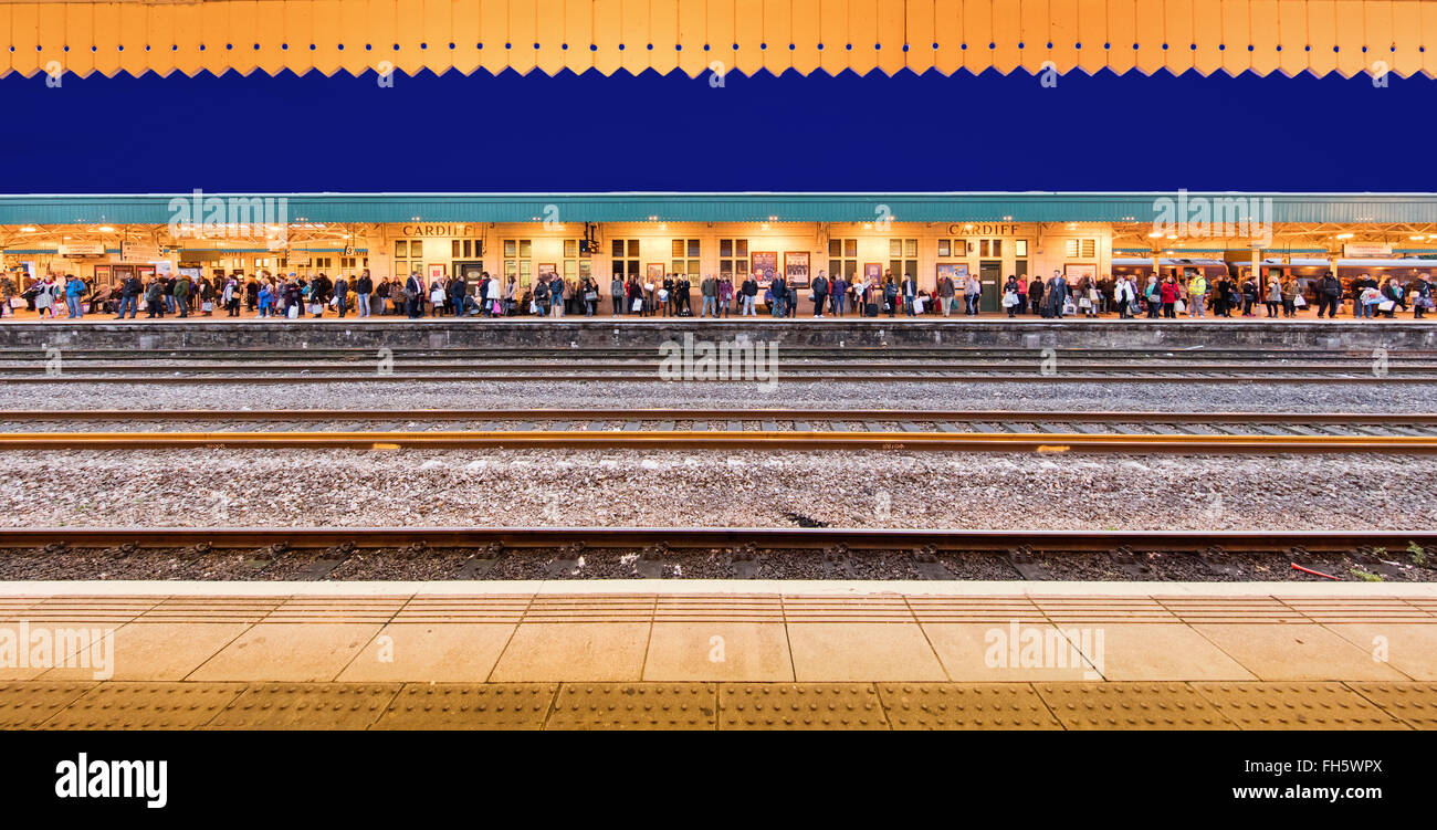 Les passagers en attente de trains sur une plate-forme à la gare de Cardiff au Pays de Galles UK en début de soirée Banque D'Images