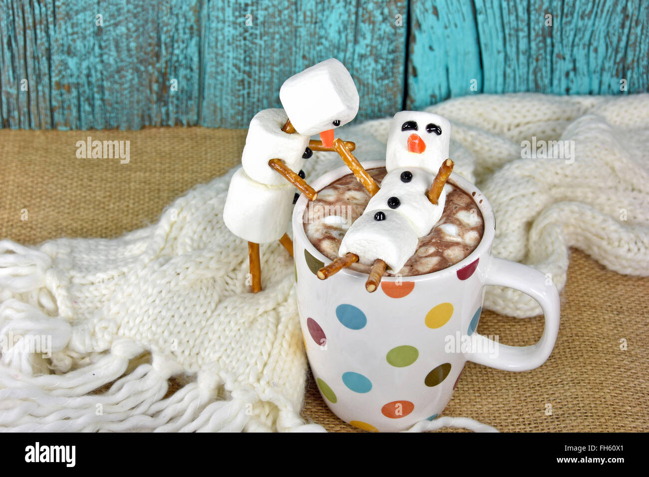 Bonhommes guimauve au chocolat chaud en verre mug à pois avec écharpe d'hiver. Banque D'Images