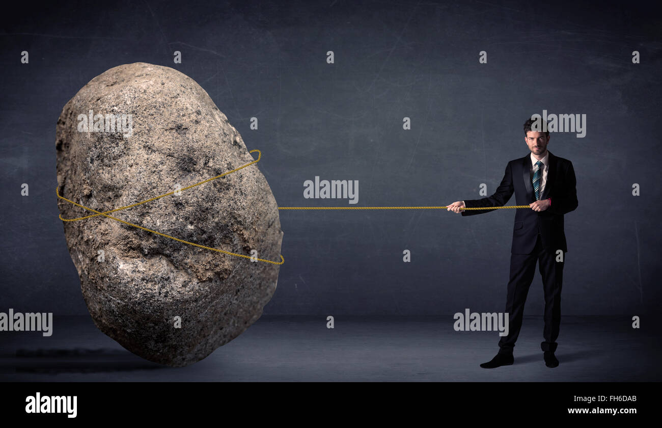 Businessman pulling énorme rocher avec une corde Banque D'Images