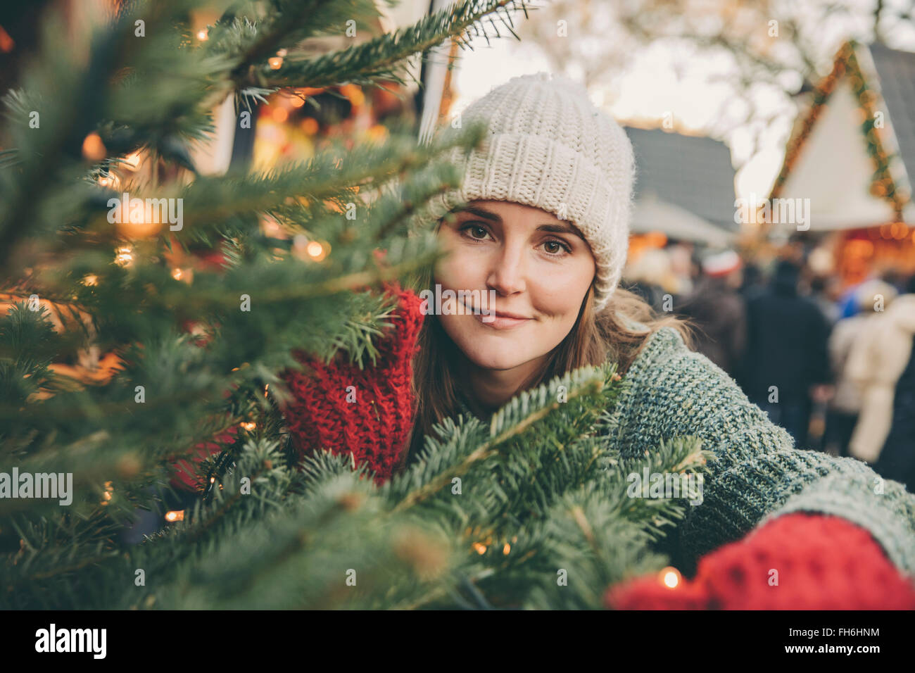 Femme à travers les branches de conifères sur le marché de Noël Banque D'Images