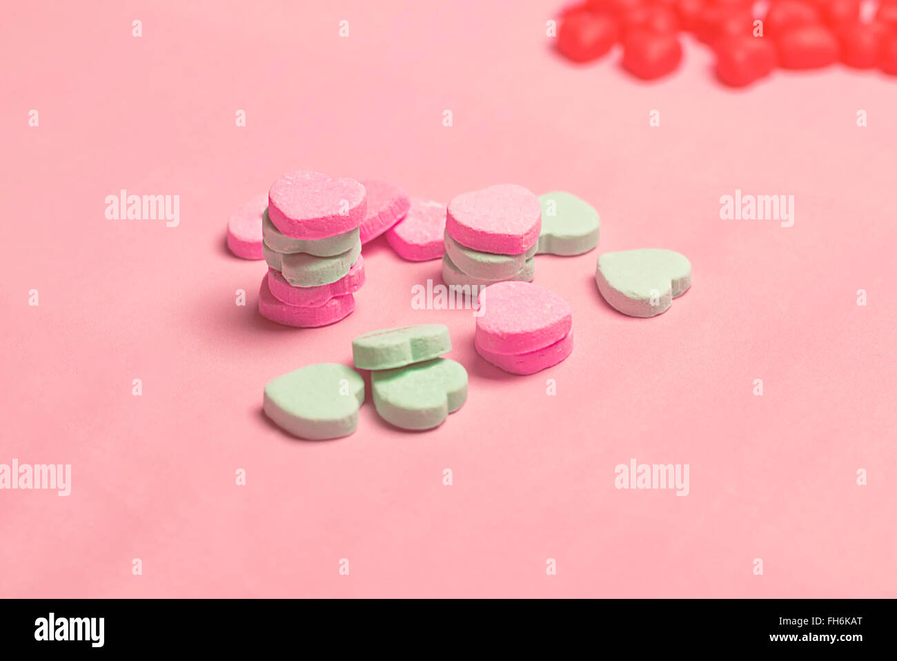 Bonbons coeur rose et vert sur fond rose pastel Banque D'Images