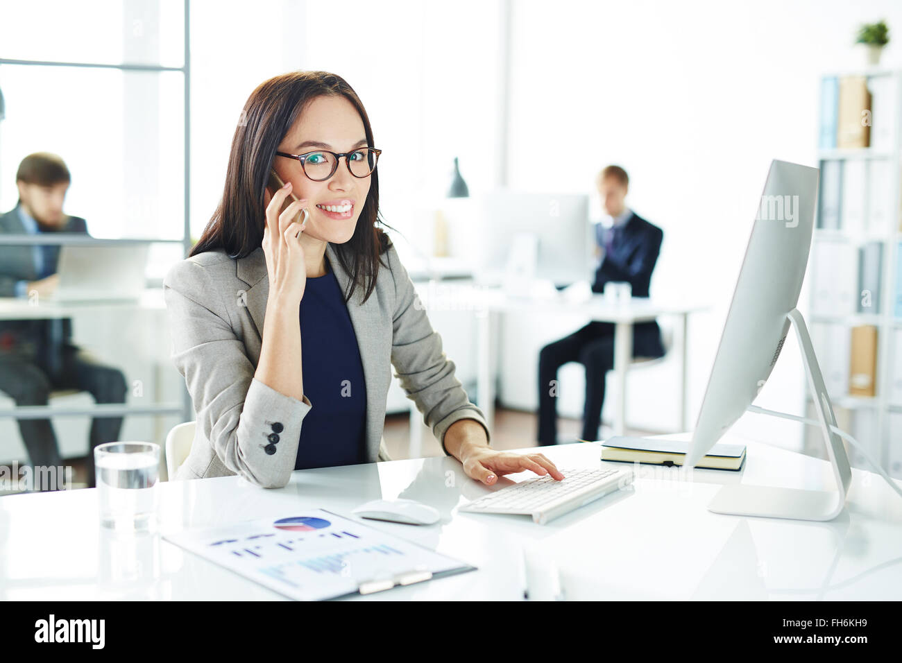 Pretty secretary looking at camera while talking on cellphone Banque D'Images