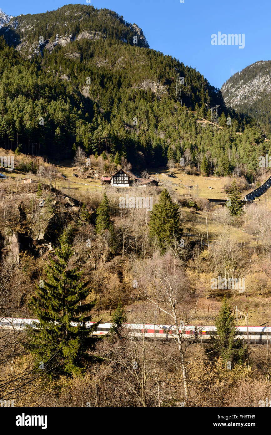 Train passant sous un chalet sur un versant ensoleillé près de Wassen , Suisse Banque D'Images
