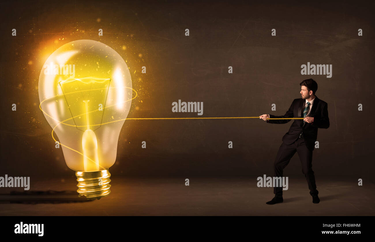 L'homme d'affaires en tirant une grosse ampoule incandescent lumineux Banque D'Images