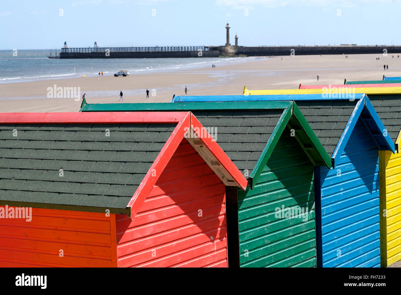 La mer du Nord et West Pier de la falaise des cabines de plage, Whitby, North Yorkshire, Angleterre Banque D'Images