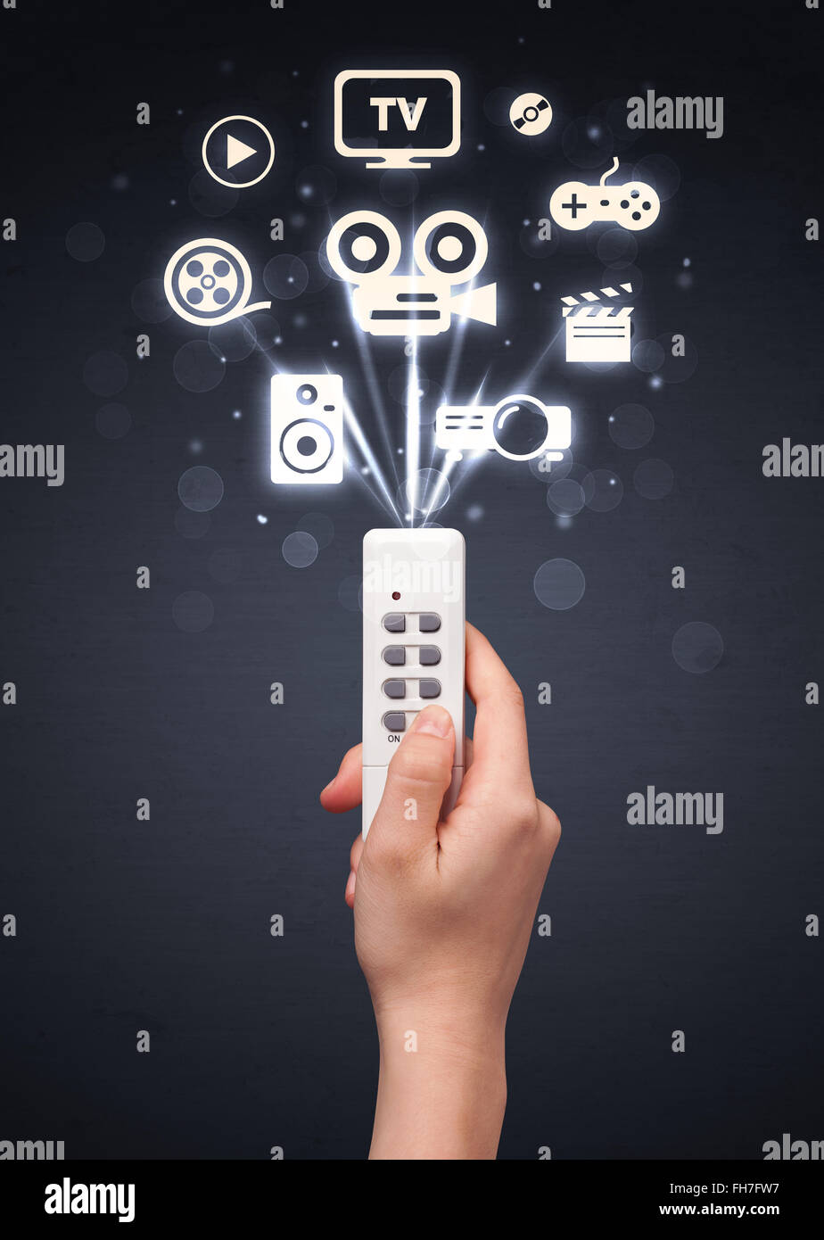 La main avec la commande à distance et les icônes des médias Banque D'Images