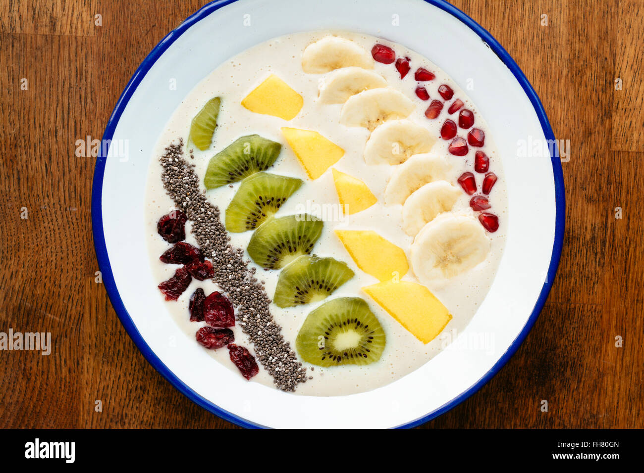 Smoothie banane bol avec kiwi, mangue, banane, chia seeds, canneberges séchées et pommegranate arils comme garniture. Banque D'Images