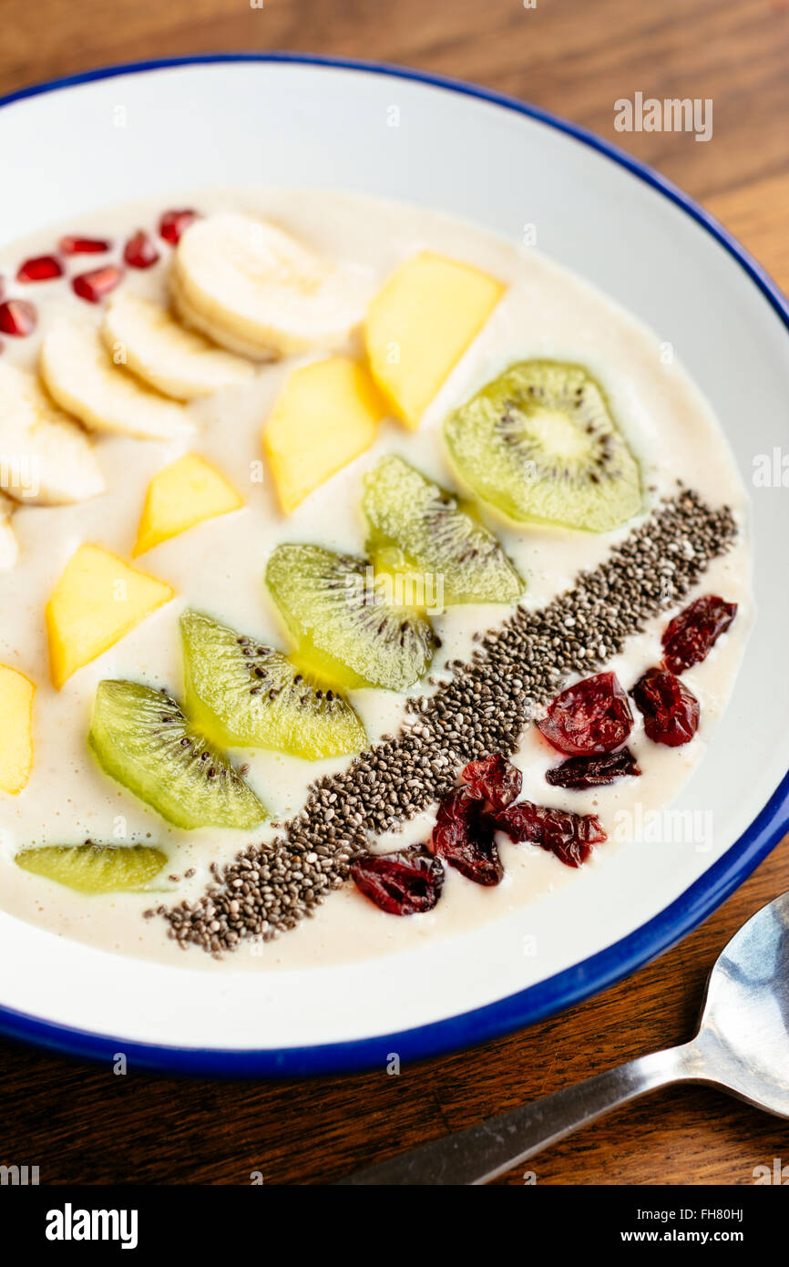 Smoothie banane bol avec kiwi, mangue, banane, chia seeds, canneberges séchées et pommegranate arils comme garniture. Banque D'Images