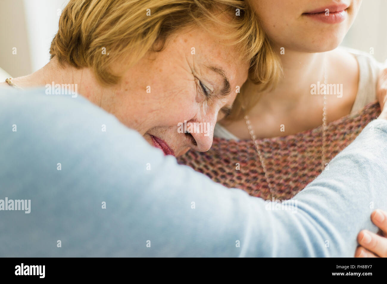 Senior woman with closed eyes appuyé contre l'épaule de la jeune femme Banque D'Images