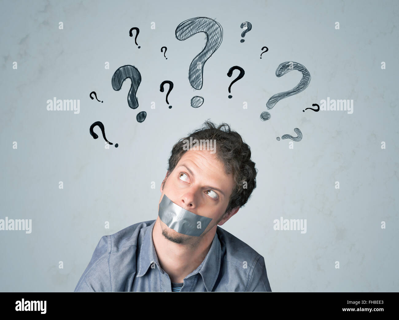 Jeune homme avec la bouche collée et symboles d'interrogation Banque D'Images