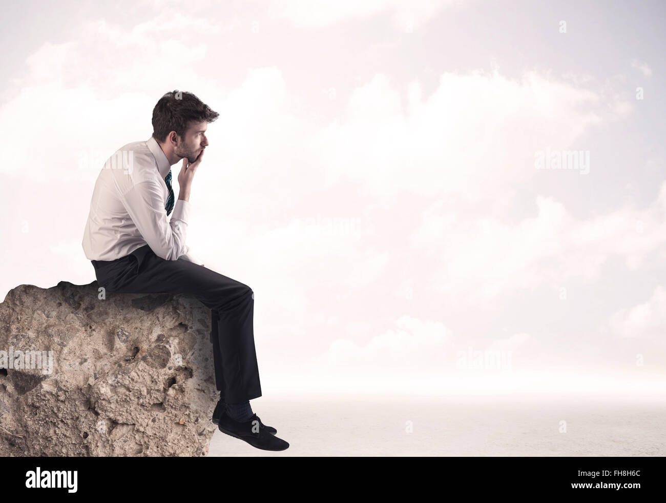 Business man sitting on stone edge Banque D'Images