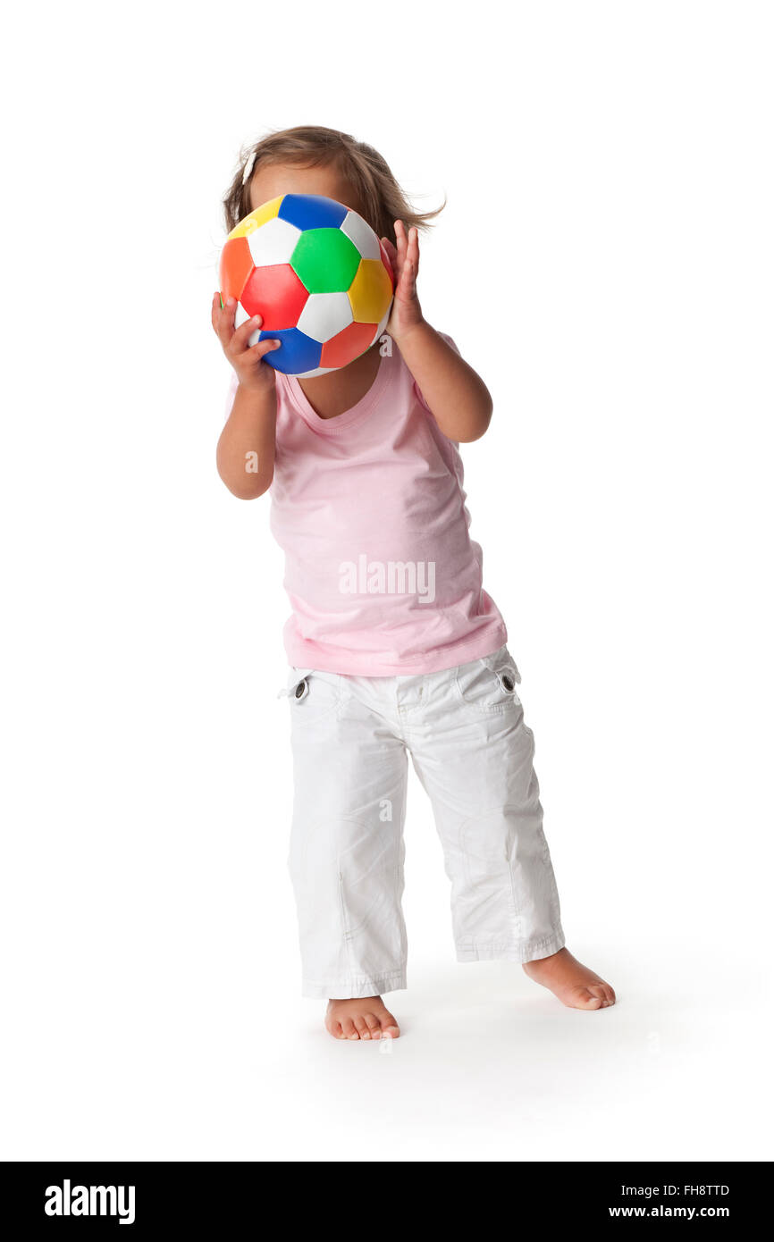 Bébé fille se cacher derrière une balle de couleur sur fond blanc Banque D'Images