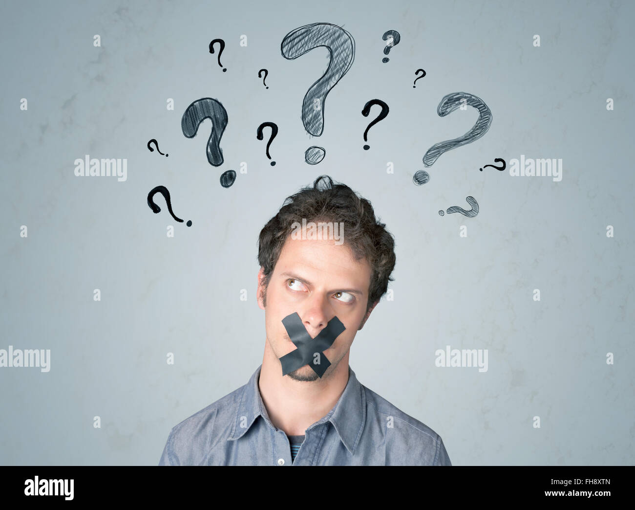 Jeune homme avec la bouche collée et symboles d'interrogation Banque D'Images