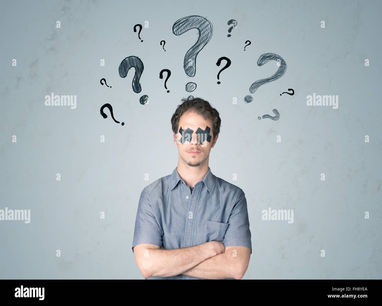 Jeune homme avec des yeux collés et symboles d'interrogation Banque D'Images