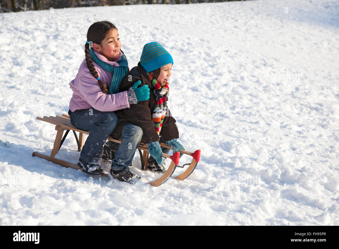 Deux enfants sur une luge dans la neige Banque D'Images