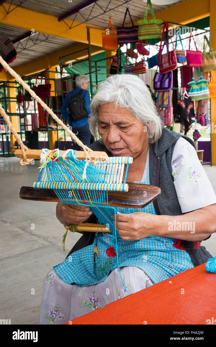 Santo Tomás Jalietza, Oaxaca, Mexique - une femme travaille sur un métier à sangle arrière à une coopérative de tisserandes marché. Banque D'Images