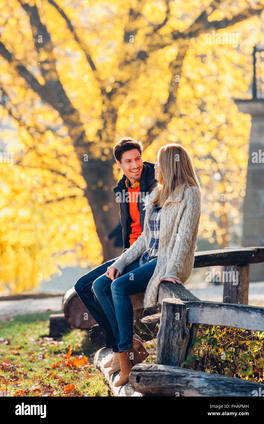 Heureux couple sitting on balustrade de bois dans le parc en automne Banque D'Images