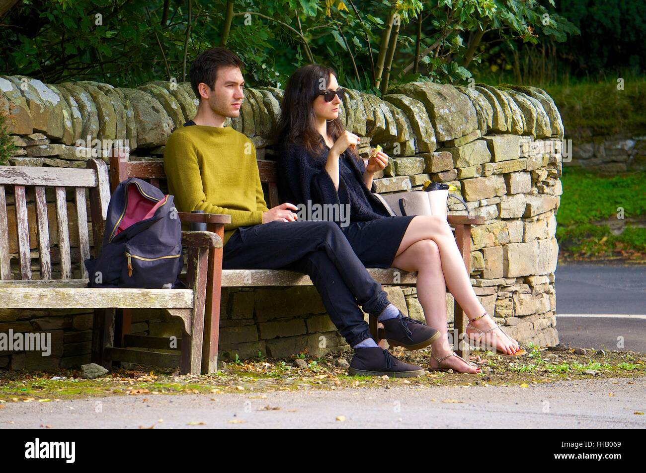 Jeune couple assis sur un banc, profitant du soleil. Banque D'Images