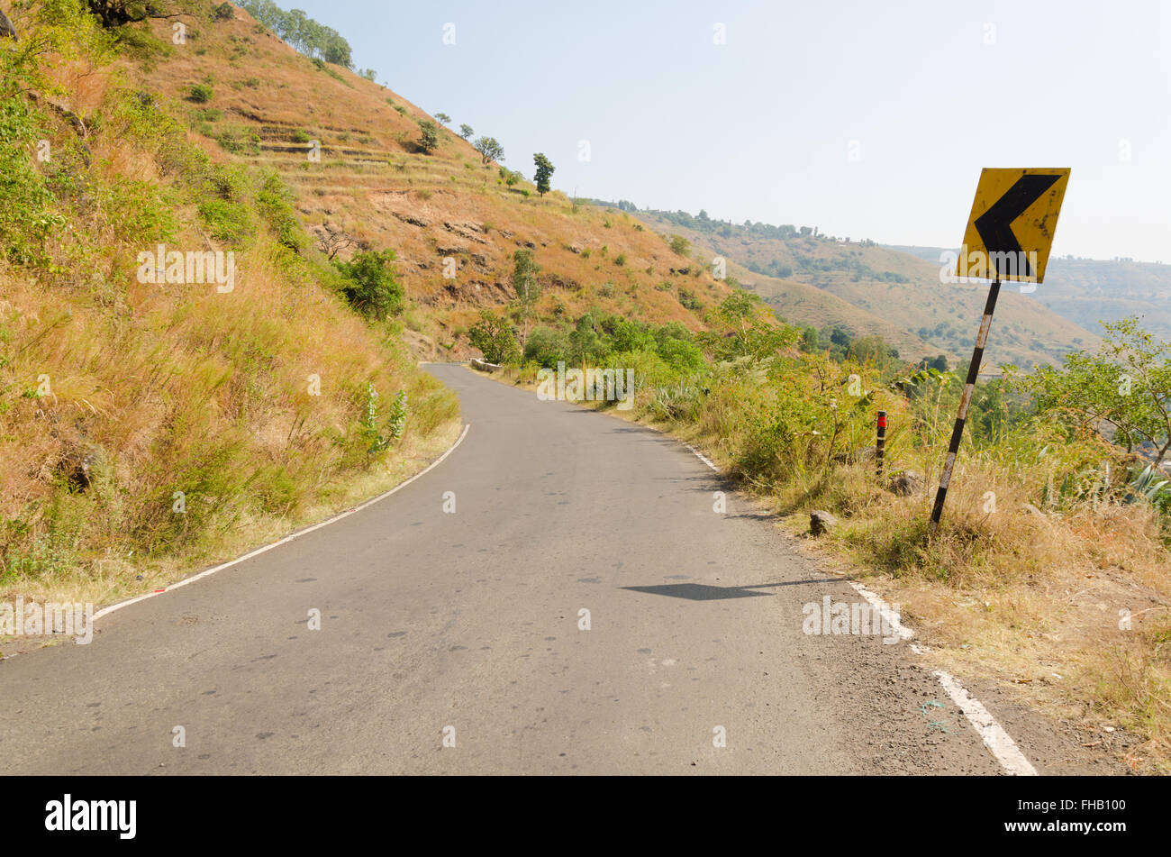 Flèche gauche street sign dans le virage d'une route de montagne à Panchgani, Maharashtra, Inde. Banque D'Images