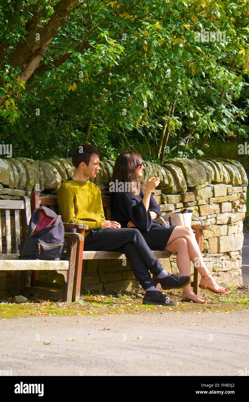 Jeune couple assis sur un banc, profitant du soleil. Banque D'Images