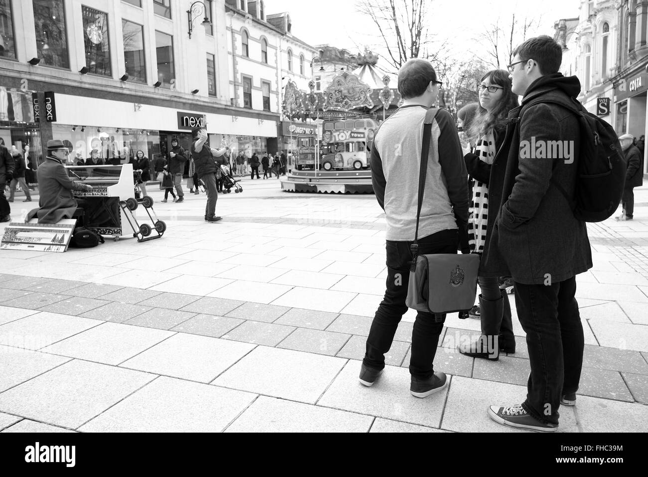 Les jeunes à Cardiff regardant un musicien de rue jouant son piano mobile. Février 2016 Banque D'Images