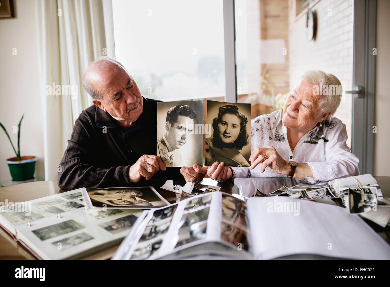 Senior couple montrant vieilles photos d'eux-mêmes Banque D'Images