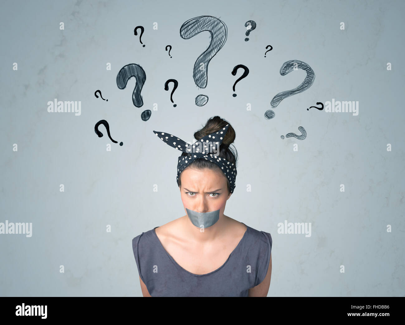 Jeune femme avec la bouche collée et symboles d'interrogation Banque D'Images