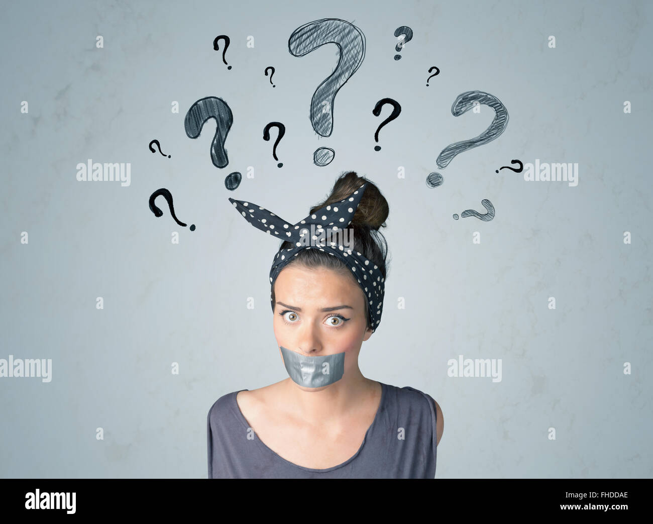 Jeune femme avec la bouche collée et symboles d'interrogation Banque D'Images