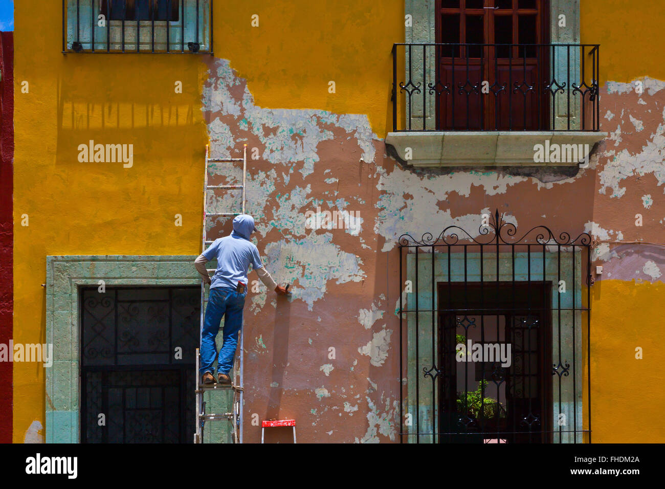Un peintre au travail dans la maisons peintes de couleurs vives et boutiques bordent les rues à Oaxaca, Mexique Banque D'Images