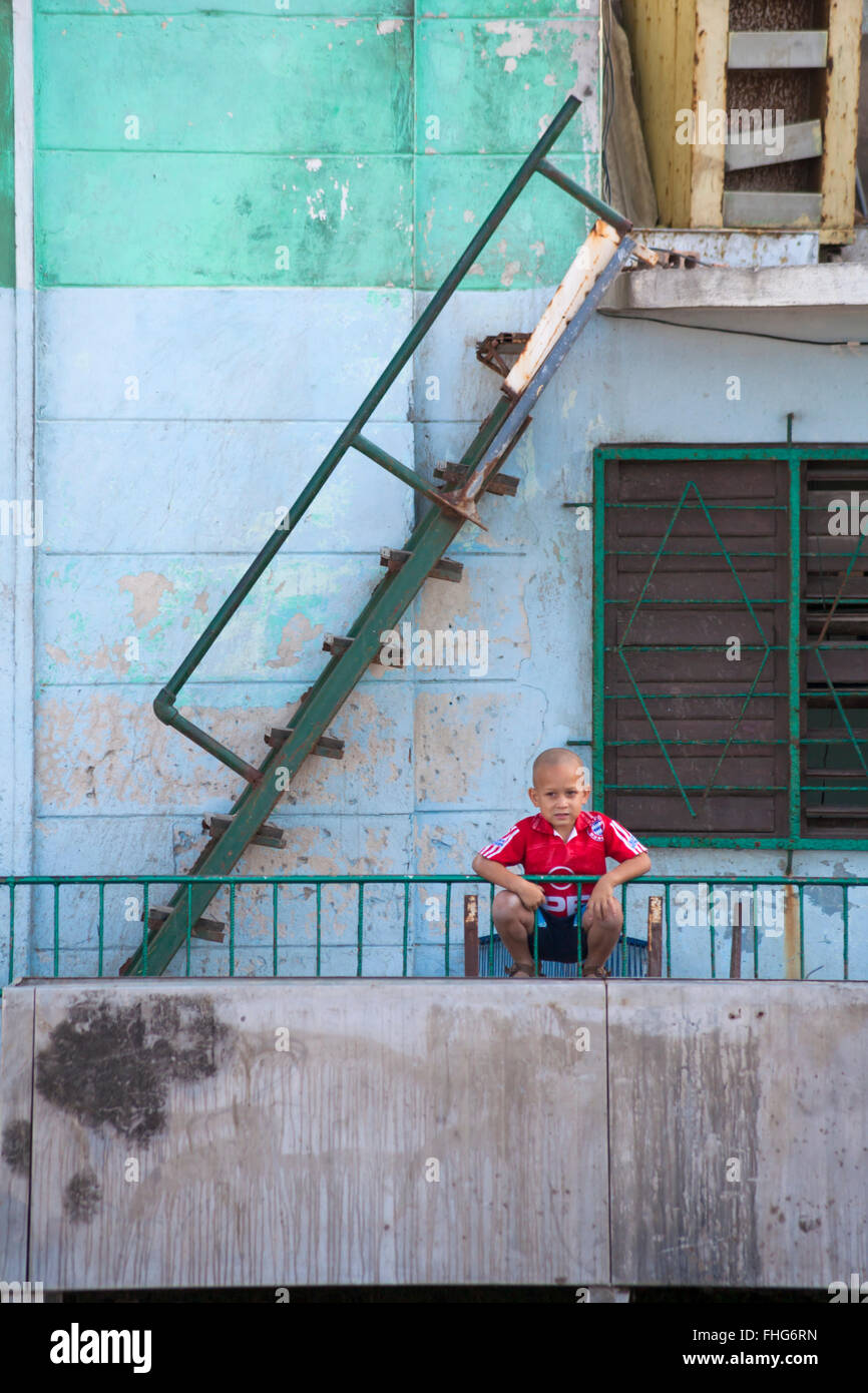 La vie quotidienne à Cuba - jeune garçon cubain s'appuyant sur les garde-corps à La Havane, Cuba, Antilles, Caraïbes, Amérique Centrale Banque D'Images