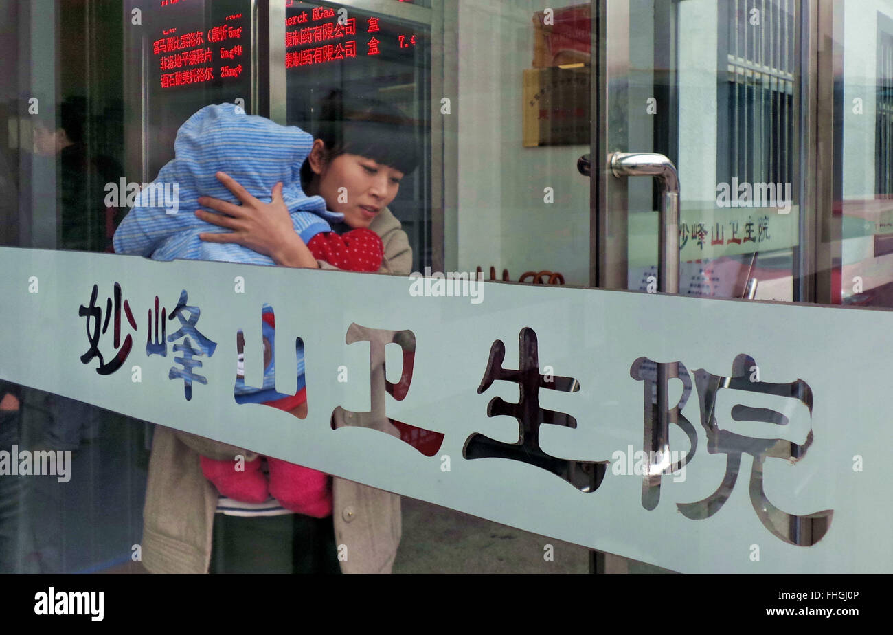 Beijing, Chine. Feb 25, 2016. Une femme tenant son bébé sort d'une clinique communautaire à Miaofengshan Township à Beijing, capitale de Chine, le 25 février 2016. En 2016, 100 cercles de service sera construit pour les collectivités à Beijing afin de fournir des services dans le secteur du commerce, de la culture, des sports, de la santé et de l'éducation qui sont accessibles en 15 minutes pour les résidents. © Li Xin/Xinhua/Alamy Live News Banque D'Images