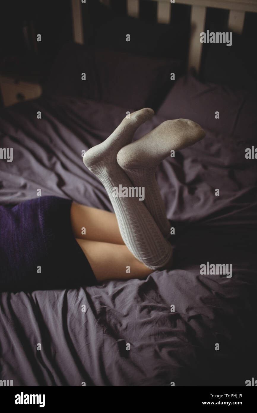 Femme allongée sur le lit avec des chaussettes Banque D'Images
