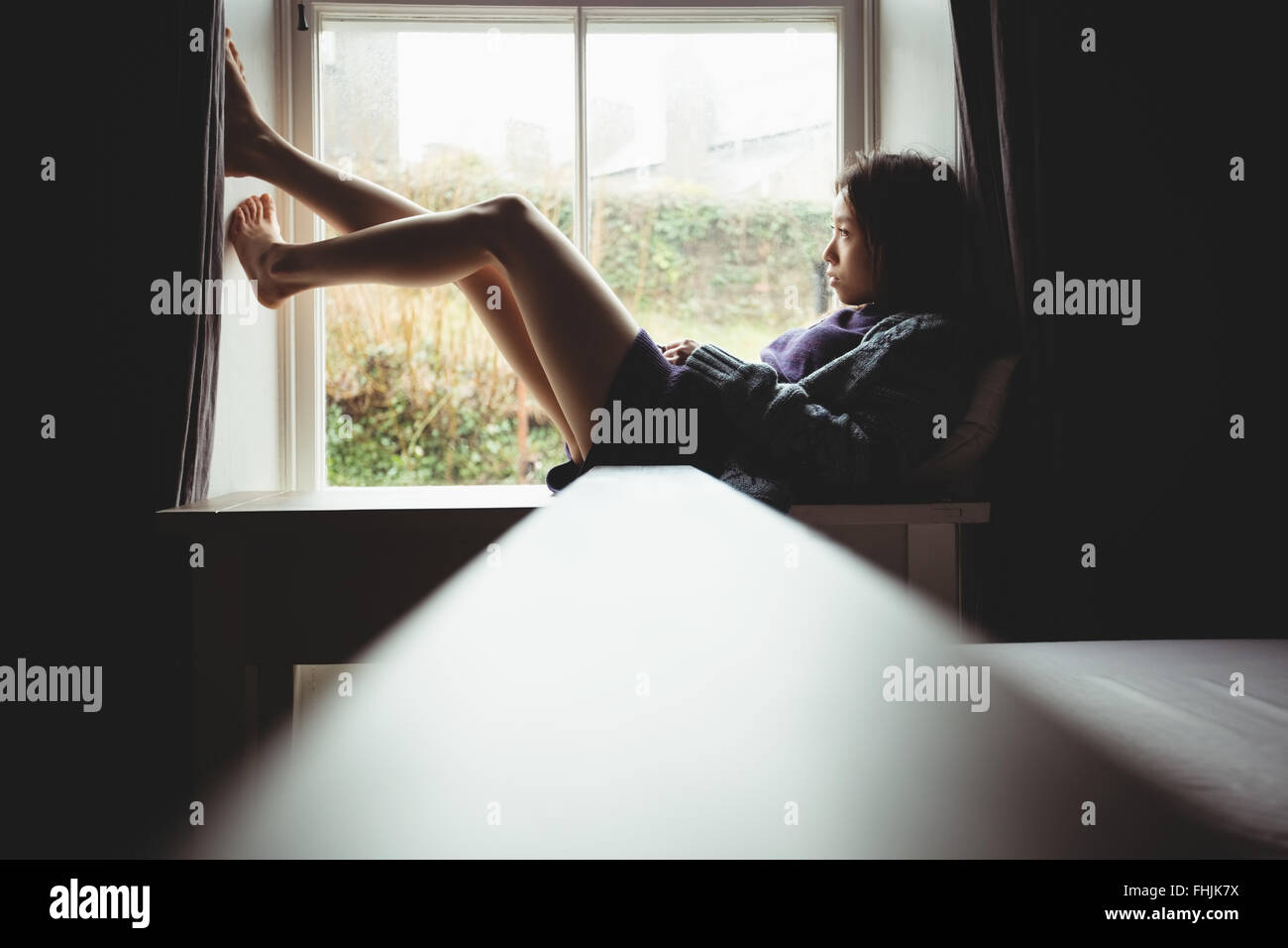 Brunette assise sur le bord de la fenêtre Banque D'Images