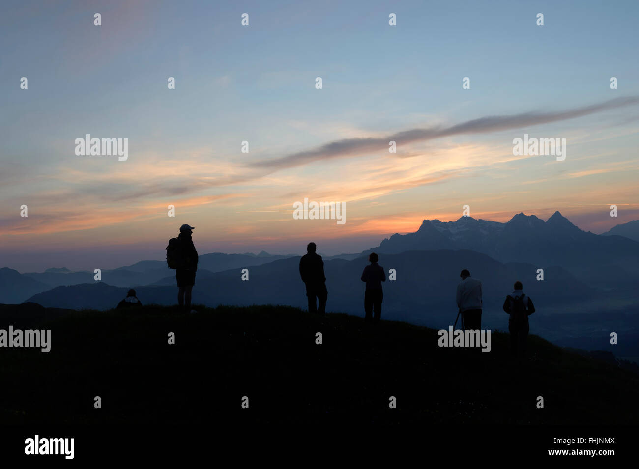 Les randonneurs regardant le lever du soleil depuis le sommet de la Kitzbüheler Horn. Le Tyrol, Autriche. Banque D'Images
