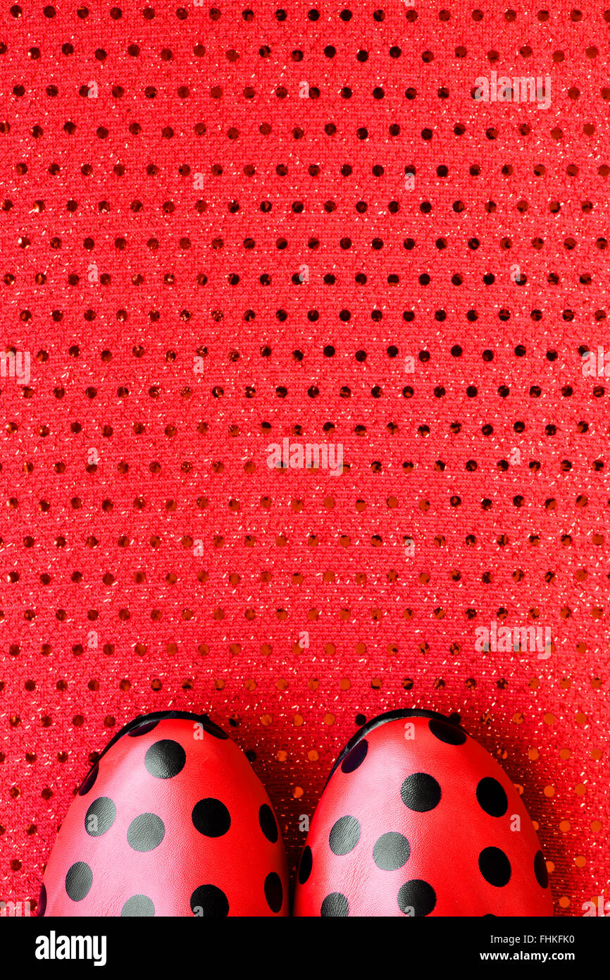 Un grand angle d'une paire de chaussures rouges à motifs de points noirs sur un point noir-rouge fond à motifs Banque D'Images