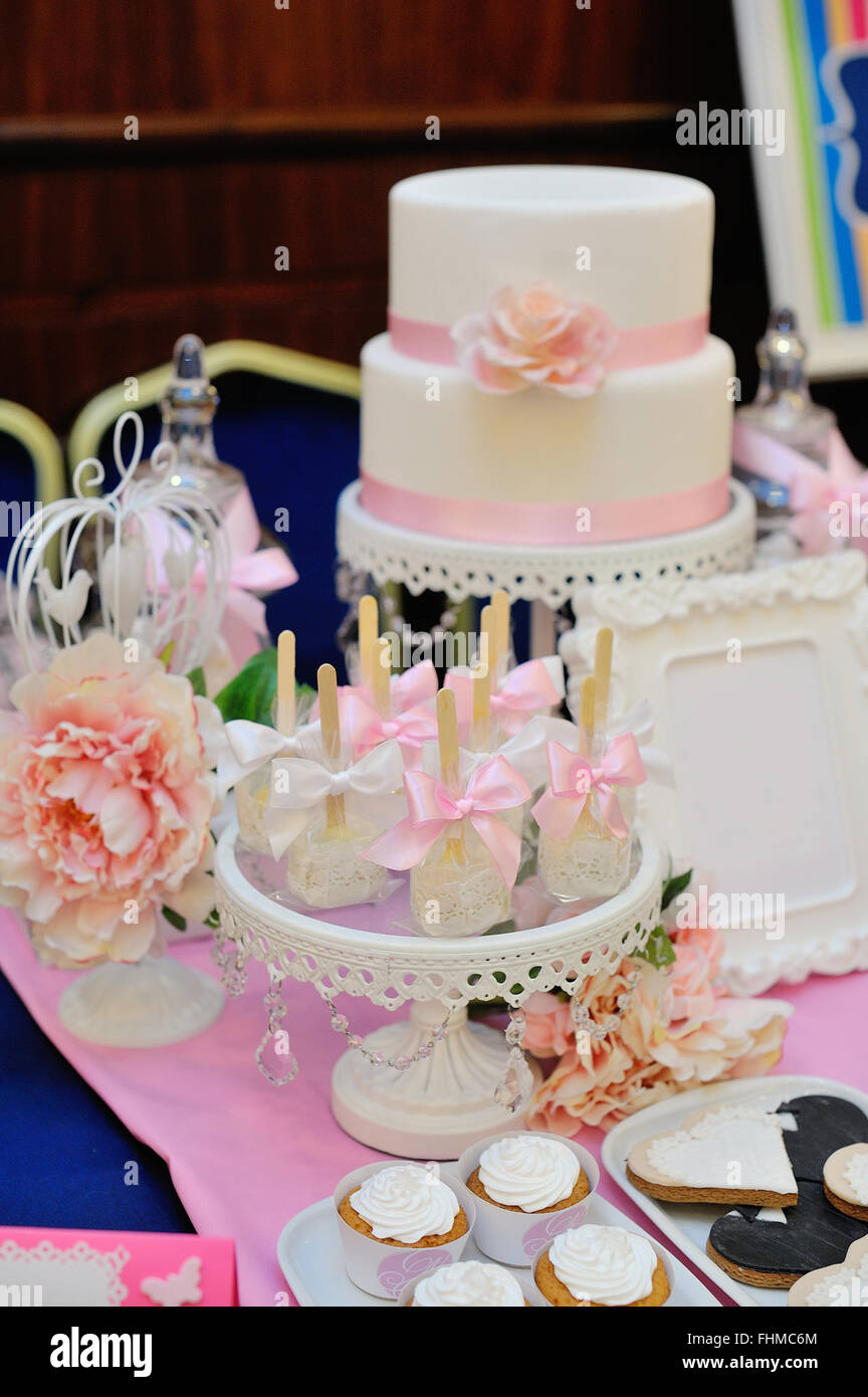 Gâteau de mariage décoré avec des roses rouges et des cupcakes Banque D'Images