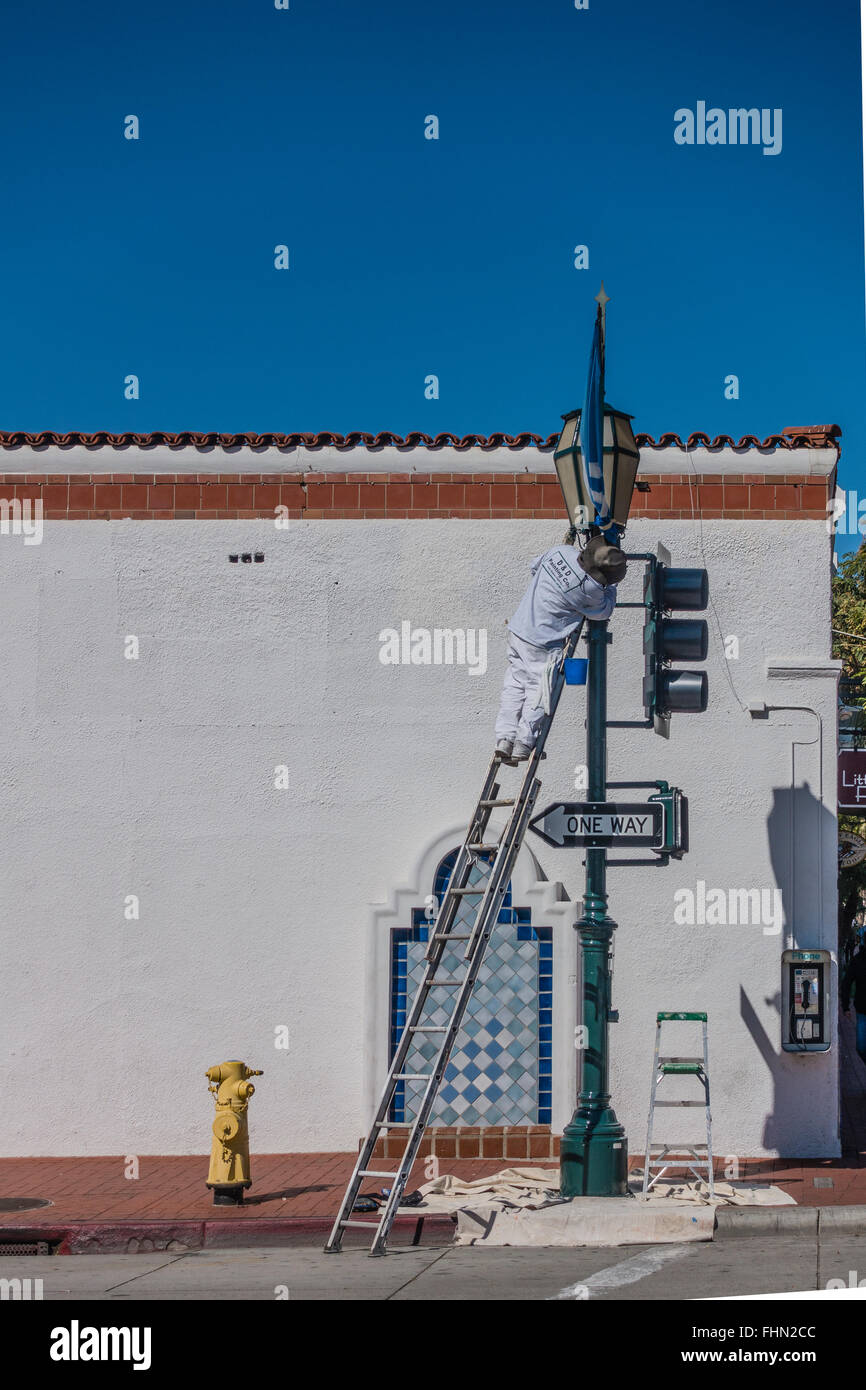 Un homme se tient sur un peintre hispanique de bain au-dessus de son vieux chiffon qu'il peint un feu de mât. Banque D'Images