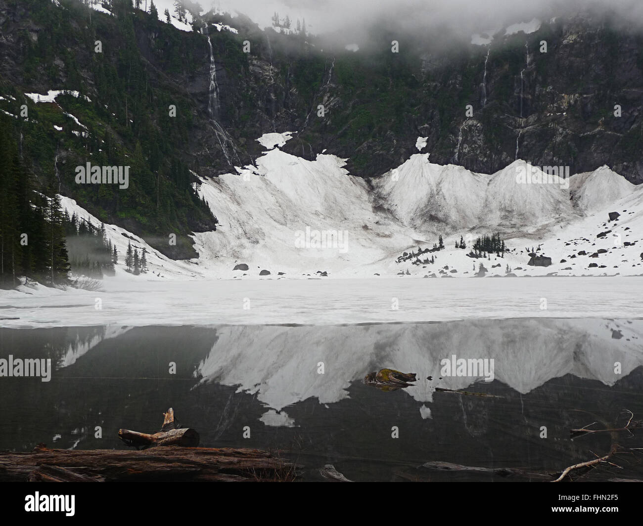 Lac alpin enneigé avec réflexion, connectez-vous en premier plan Banque D'Images