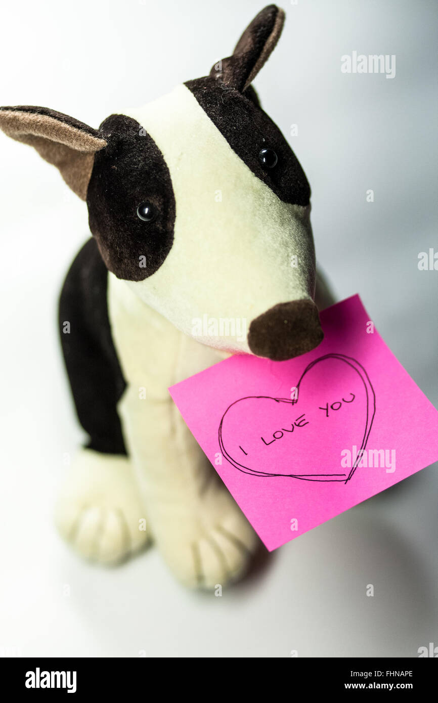 Jouet chien avec une note rose avec le message "I Love You" dans un coeur Banque D'Images