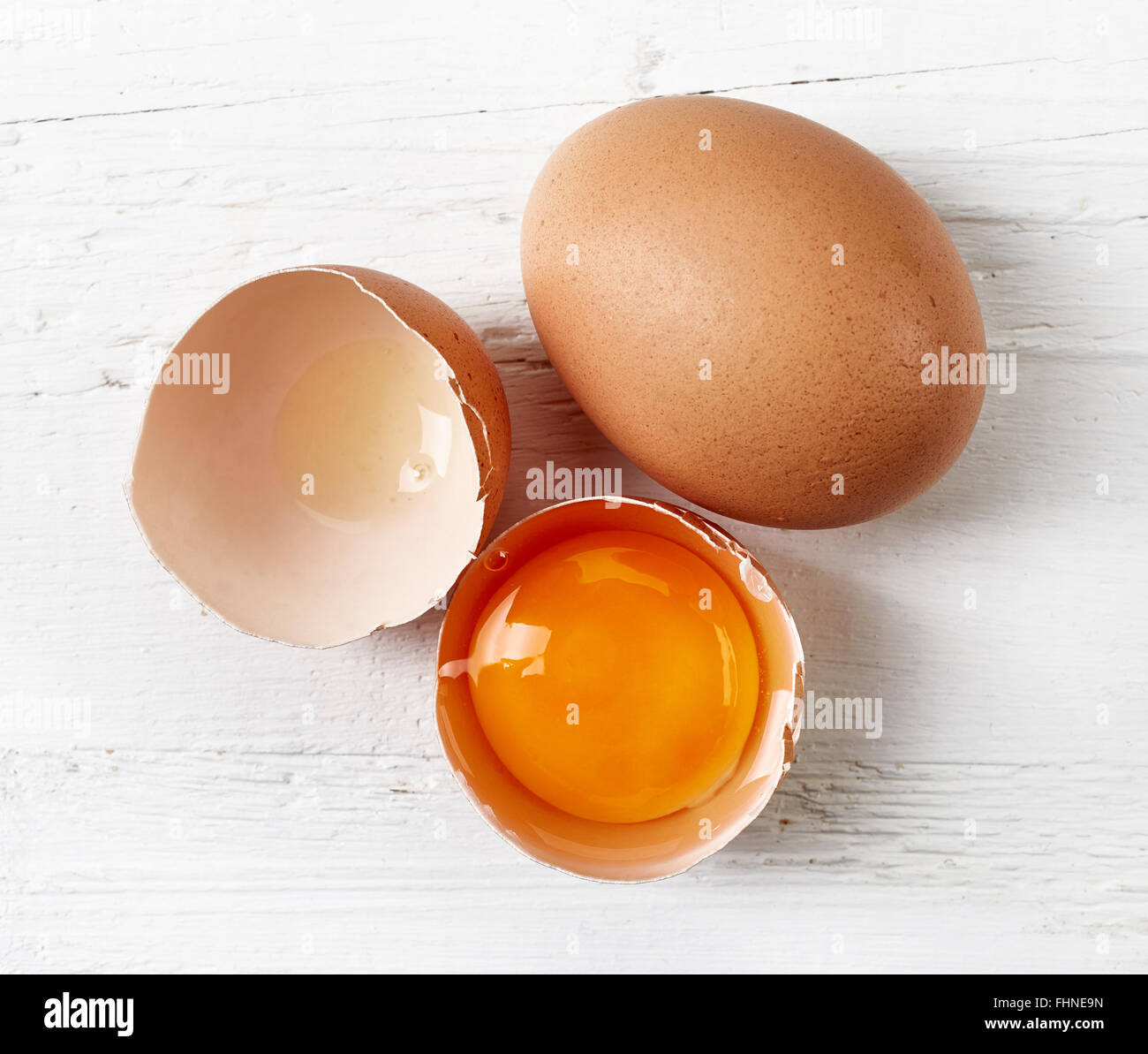 Oeufs cassés sur table en bois blanc, vue du dessus Banque D'Images