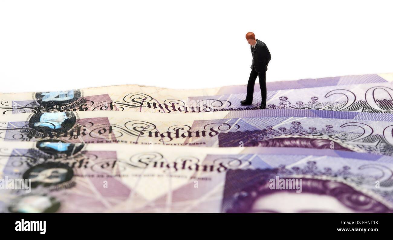 Un homme d'affaires figurine miniature dans un costume en regardant les mots Banque d'Angleterre sur quelques notes de 20 livres Banque D'Images