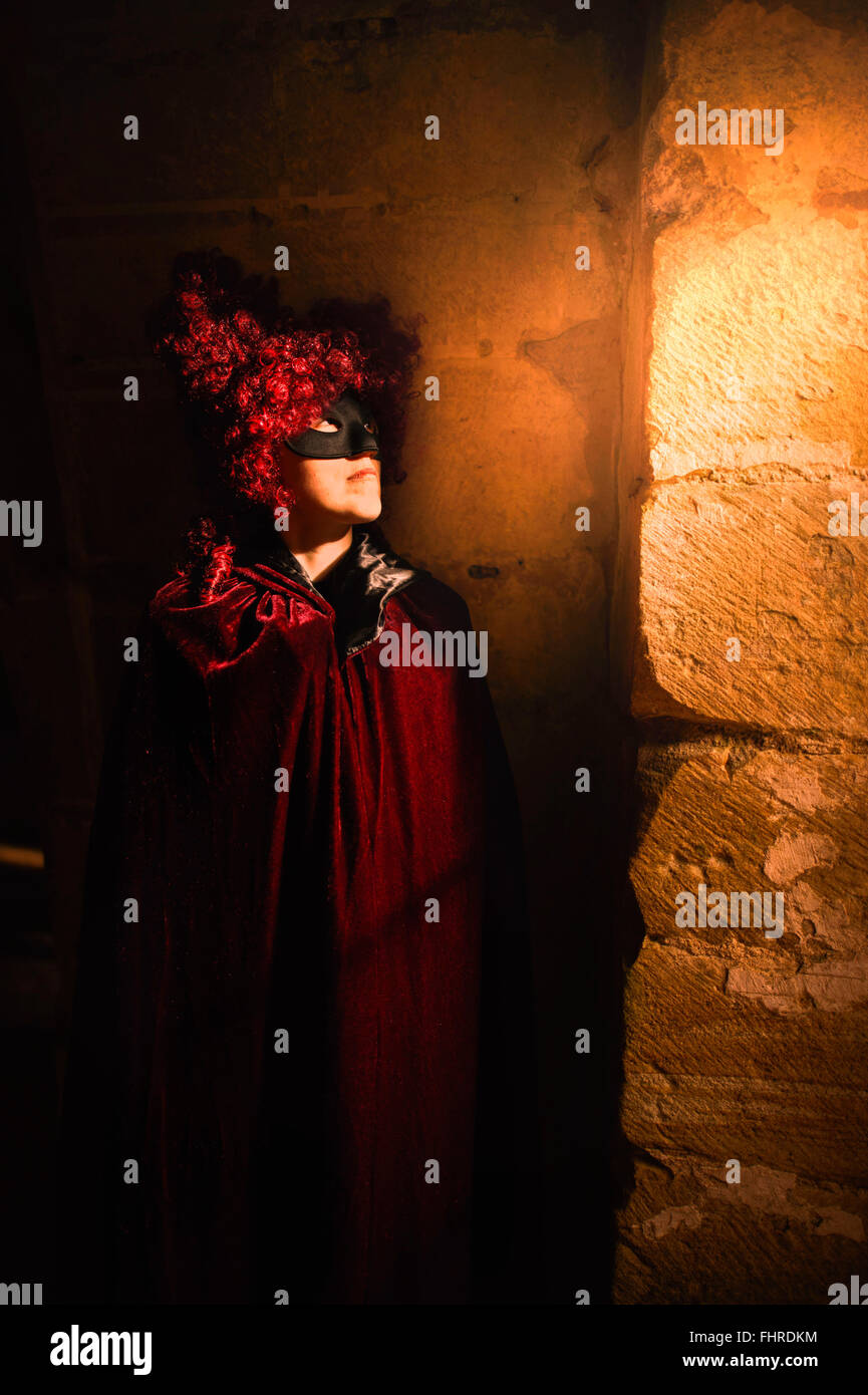 Figure féminine portant perruque rouge debout dans château par la fenêtre Banque D'Images