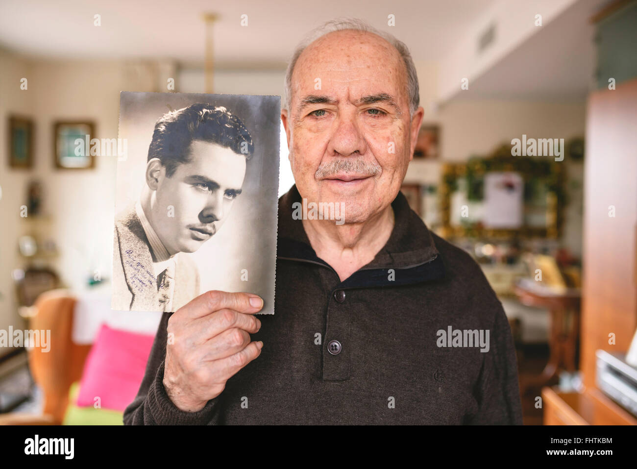 Portrait of senior man montrant une vieille photo de lui-même Banque D'Images