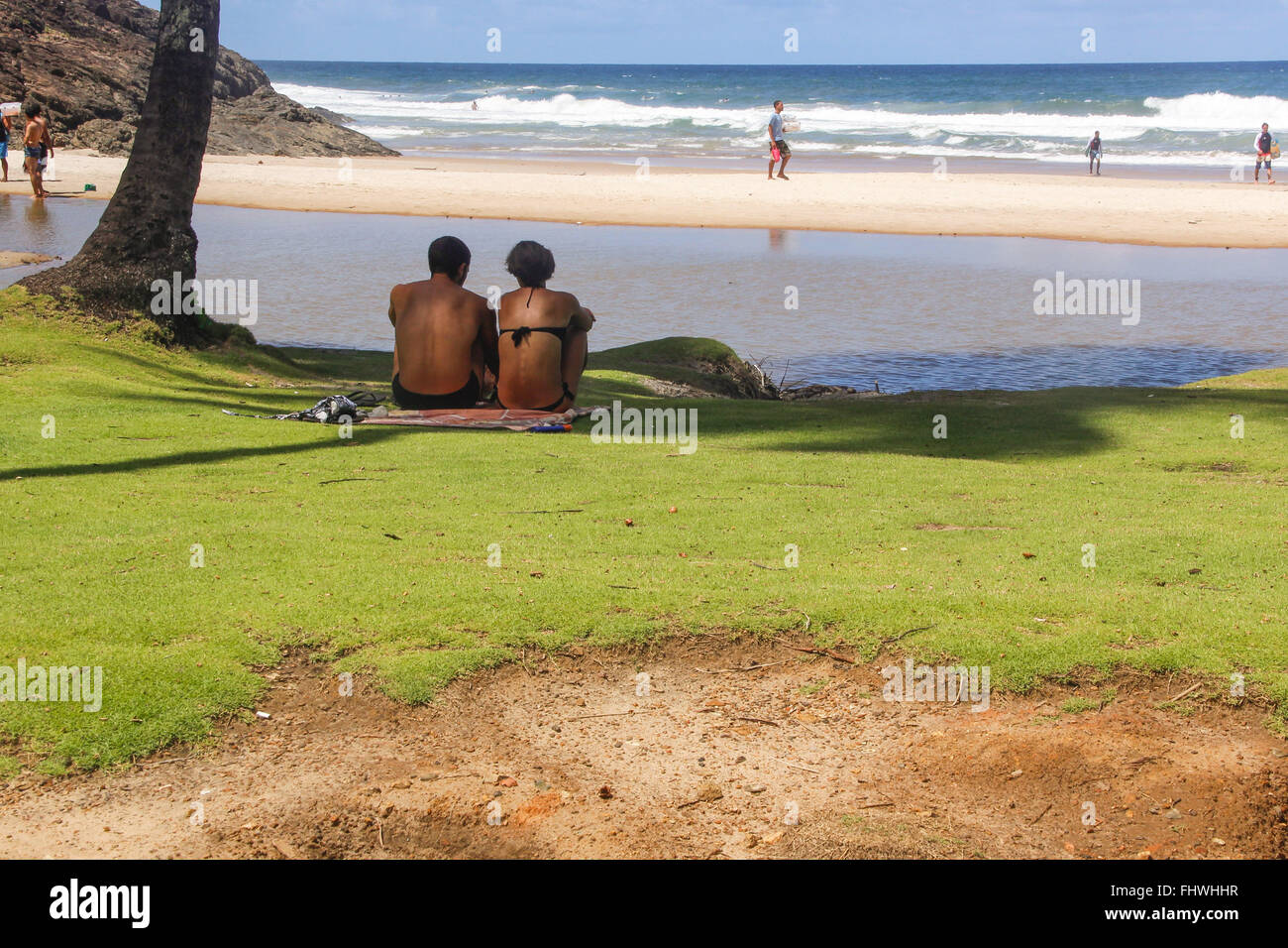 Couple assis dans l'ombre d'un arbre sur la pelouse au bord de la plage de Praia da Costa Banque D'Images