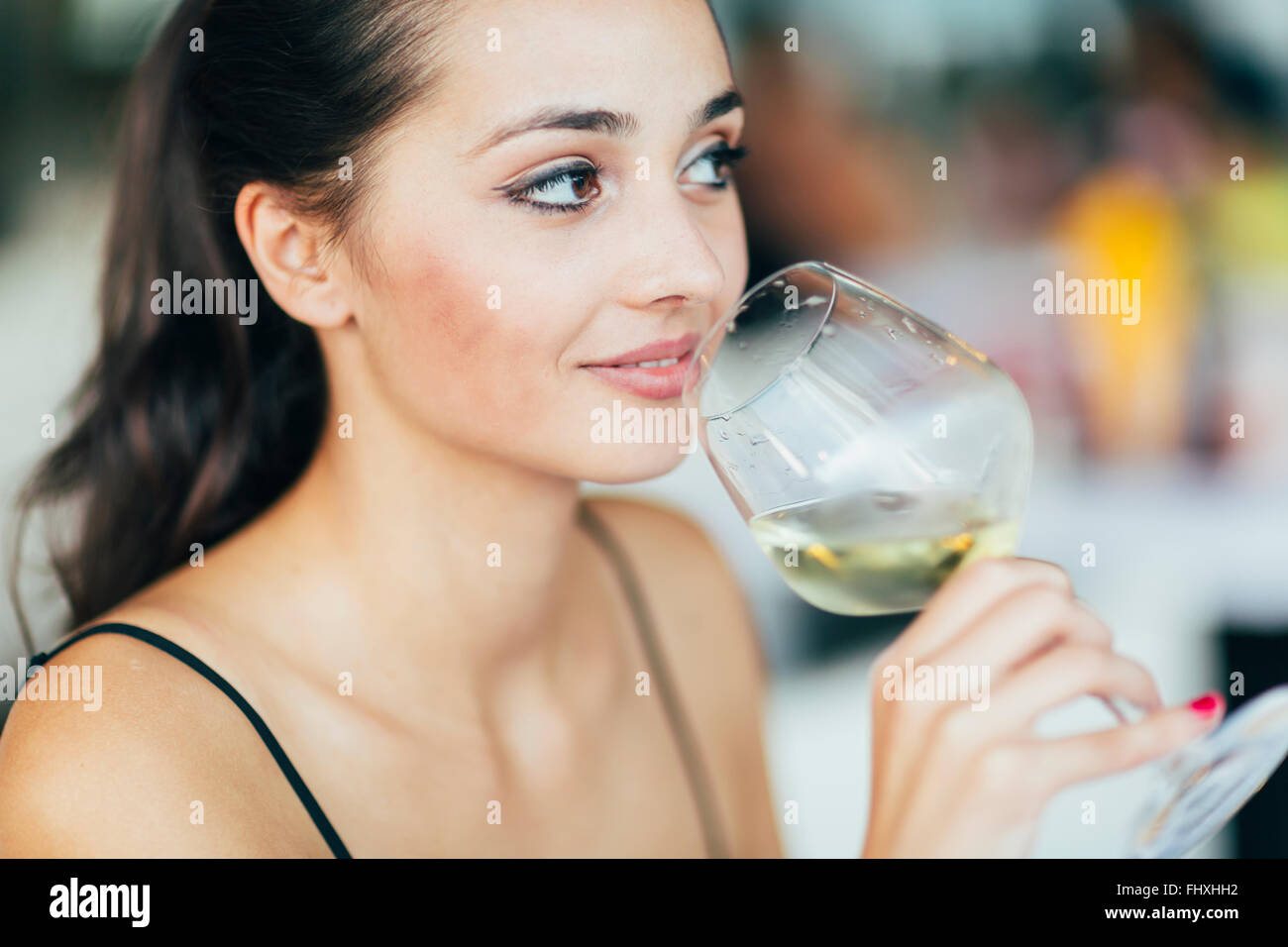 Belle femme dégustation de vin tout en sitting in restaurant Banque D'Images