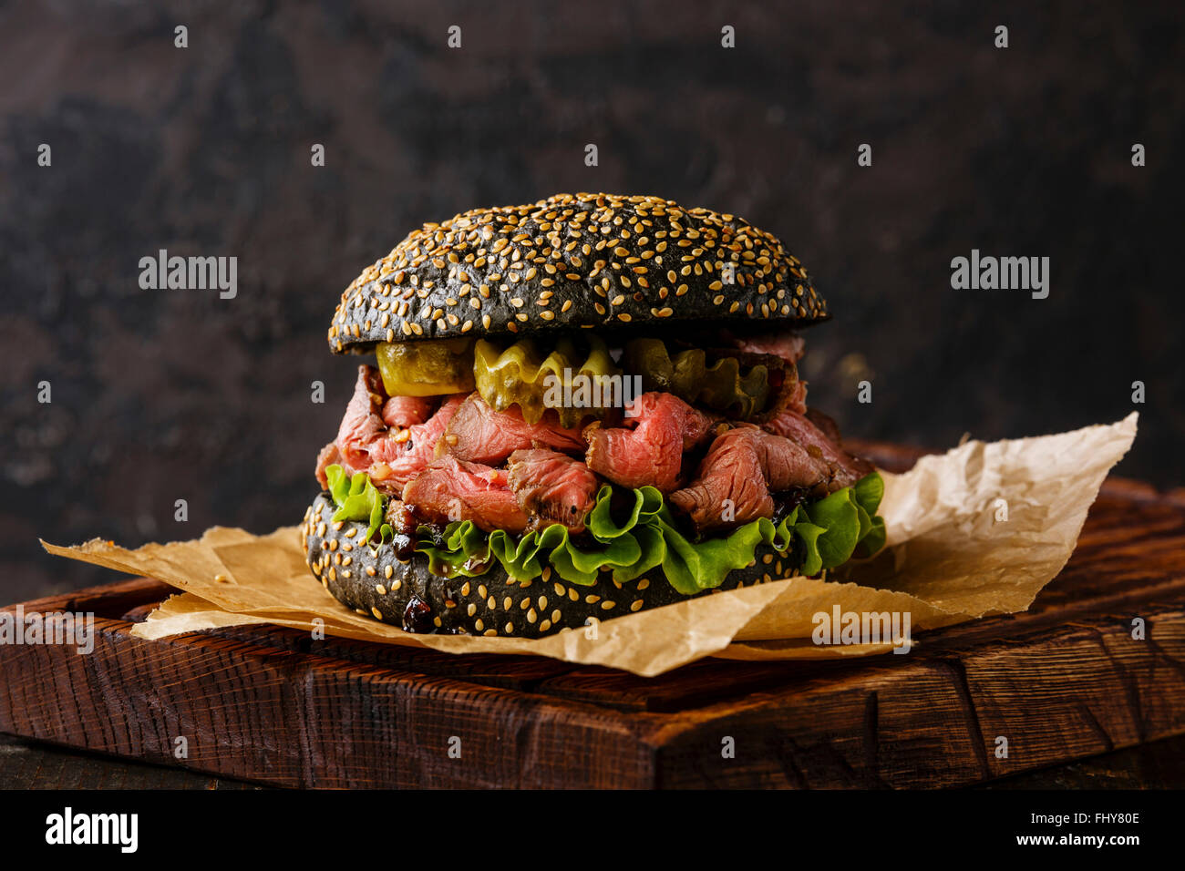 Roast Beef Burger snack à emporter sur sesame bun de tranches de Pastrami et pickle sur fond noir Banque D'Images
